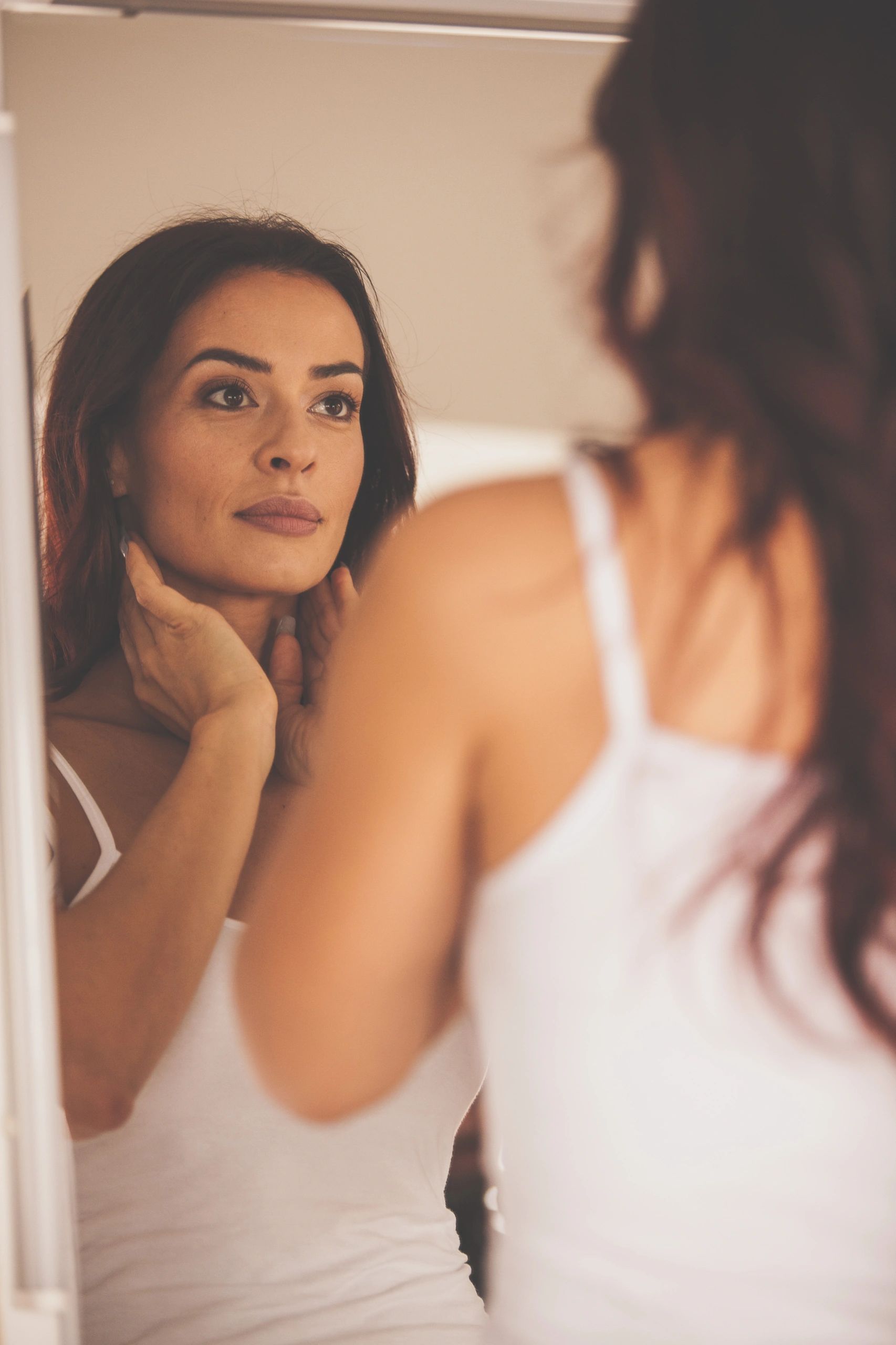 Woman admiring smoother, more radiant skin in the mirror
