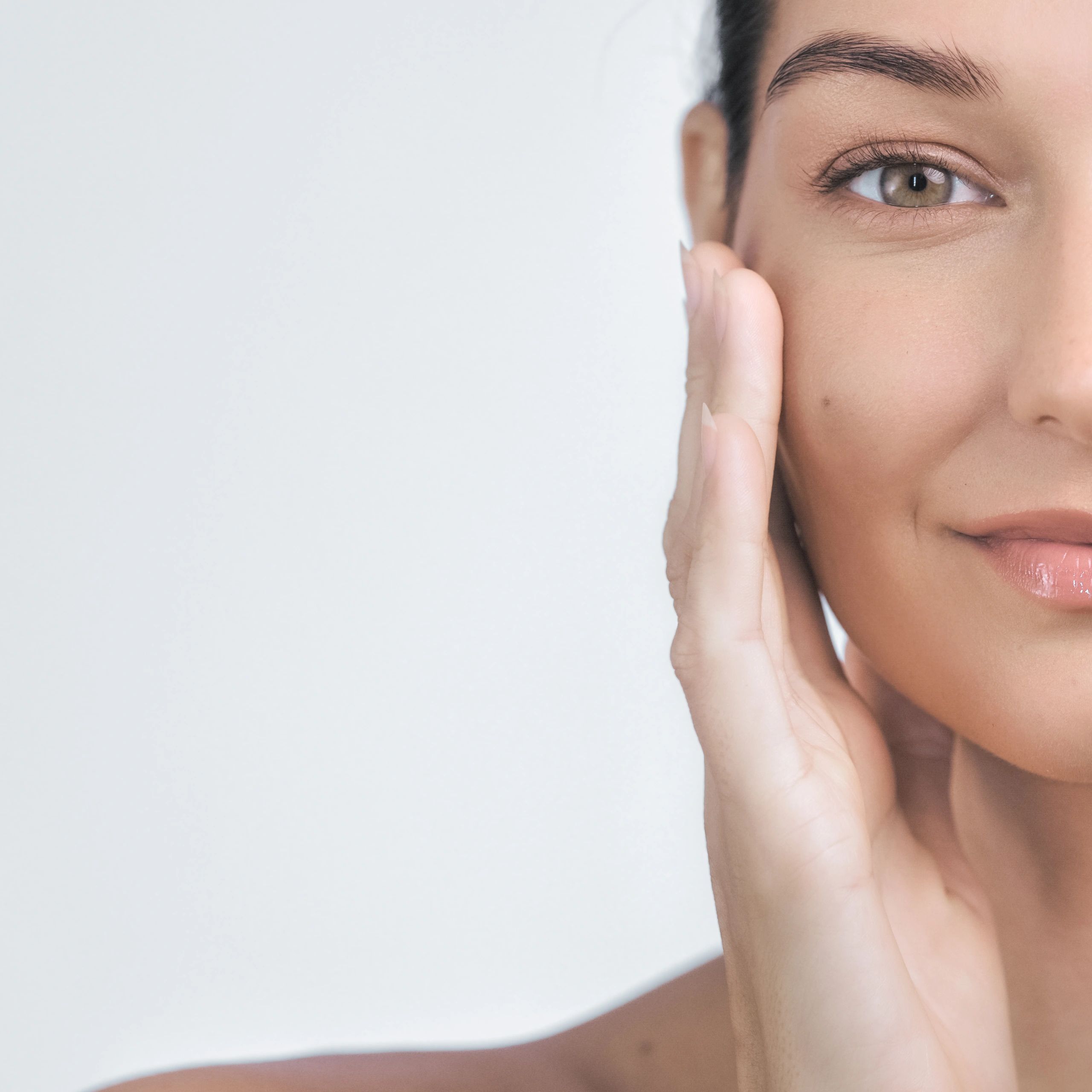 Close-up of a woman with clear glowing skin touching her face